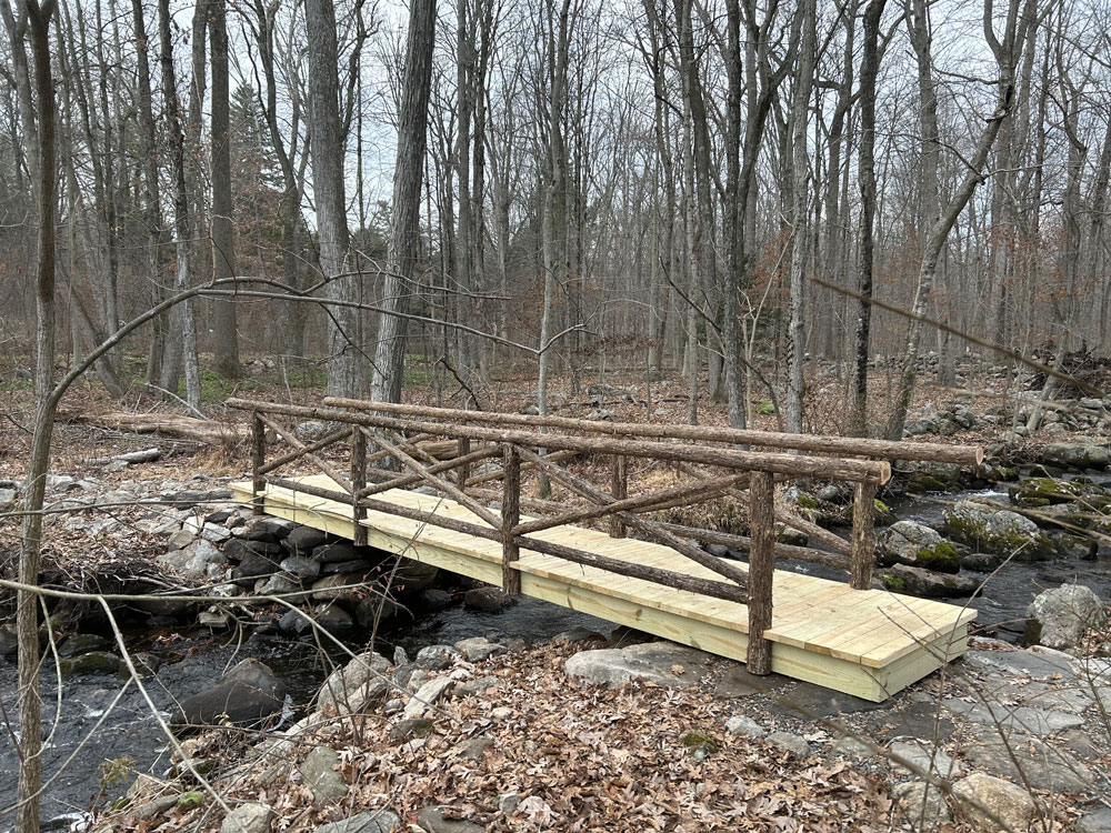 Rustic bridge built using bark-on trees and branches constructed for the Bartlett Arboretum