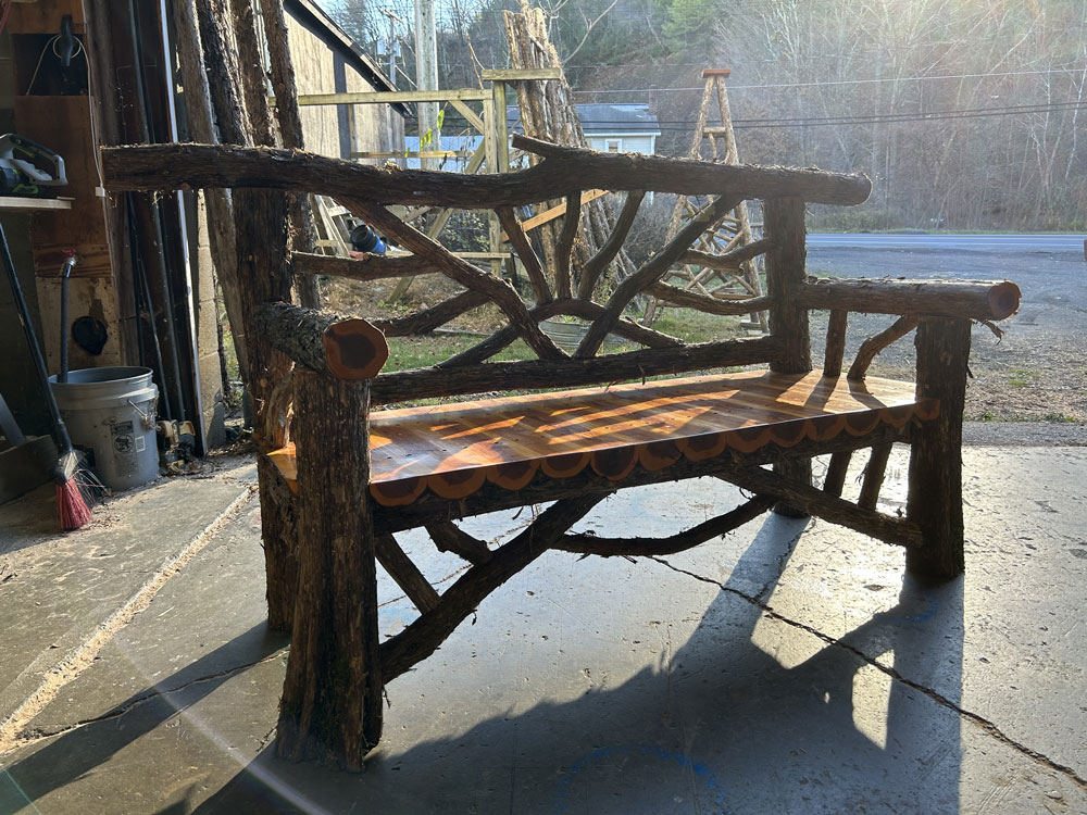 Outdoor rustic garden bench built using bark-on trees and branches titled the Catskill Bench