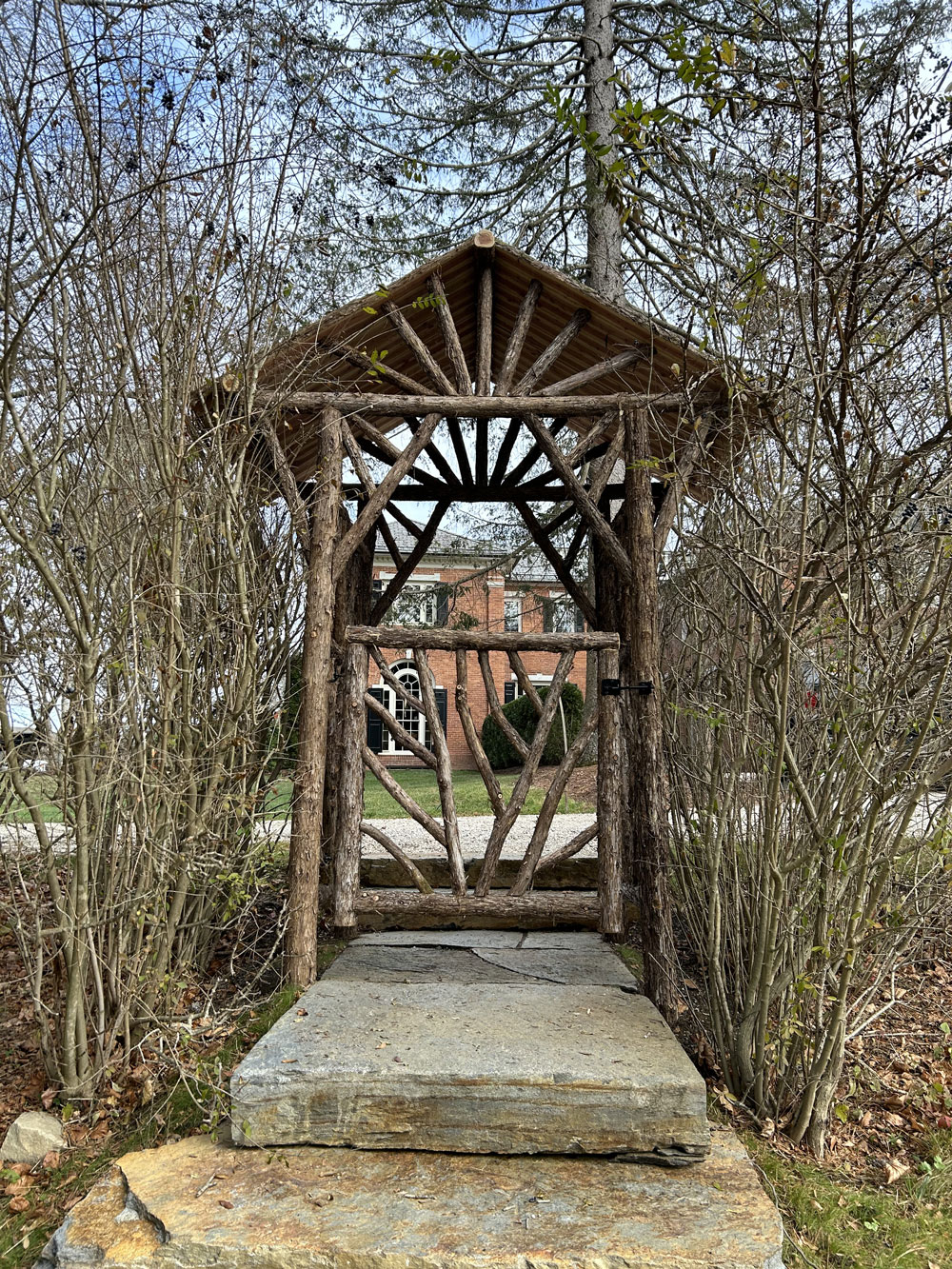 Rustic natural arbor made from bark-on cedar logs, twigs, and branches titled the Dempsey Arbor and Gate
