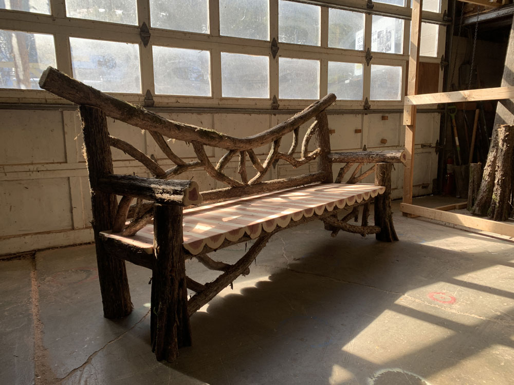Outdoor park bench built in the rustic style using logs and branches titled the Falling Waters Bench