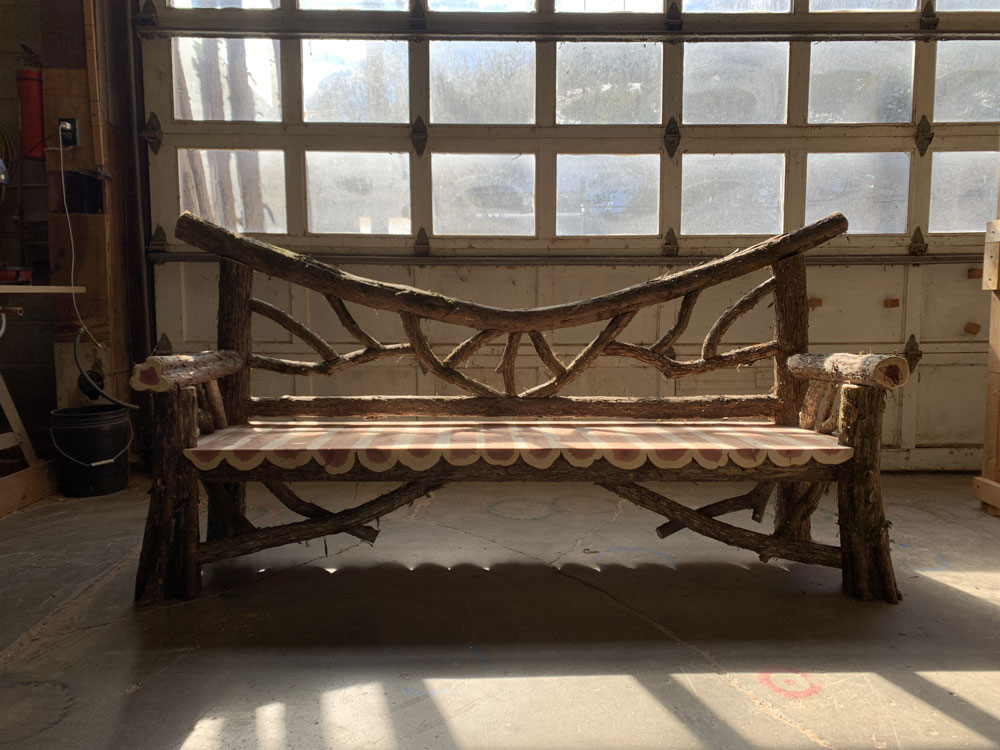 Exterior twig bench built from cedar logs titled the Falling Waters Bench