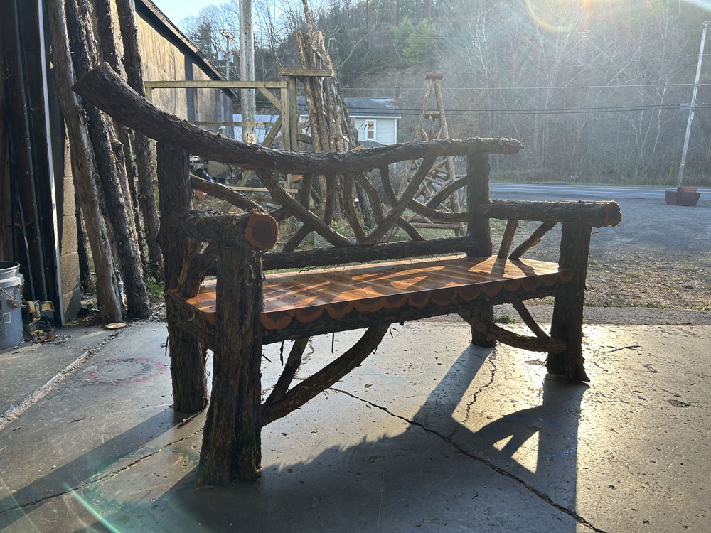 Rustic bench custom built using cedar trees and branches titled the Falling Waters Bench