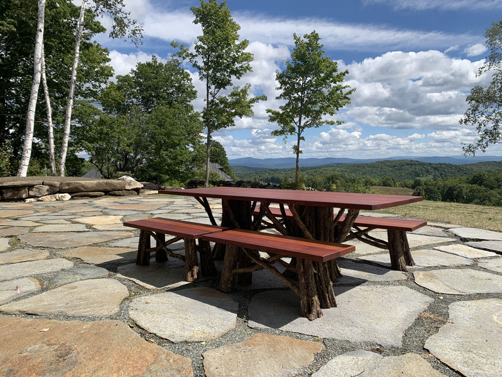 Outdoor rustic dining table and banches built using african mahagony and bark-on trees and branches titled the Healey Outdoor Dining Table