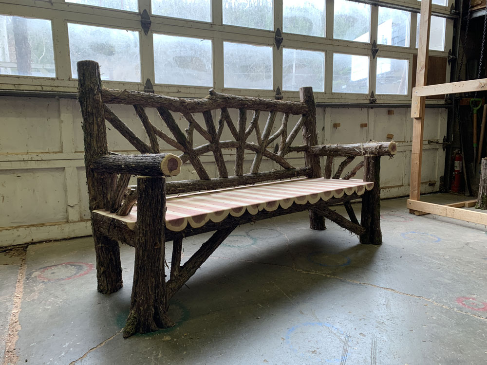 Rustic bench custom built using cedar trees and branches titled the Maverick Bench