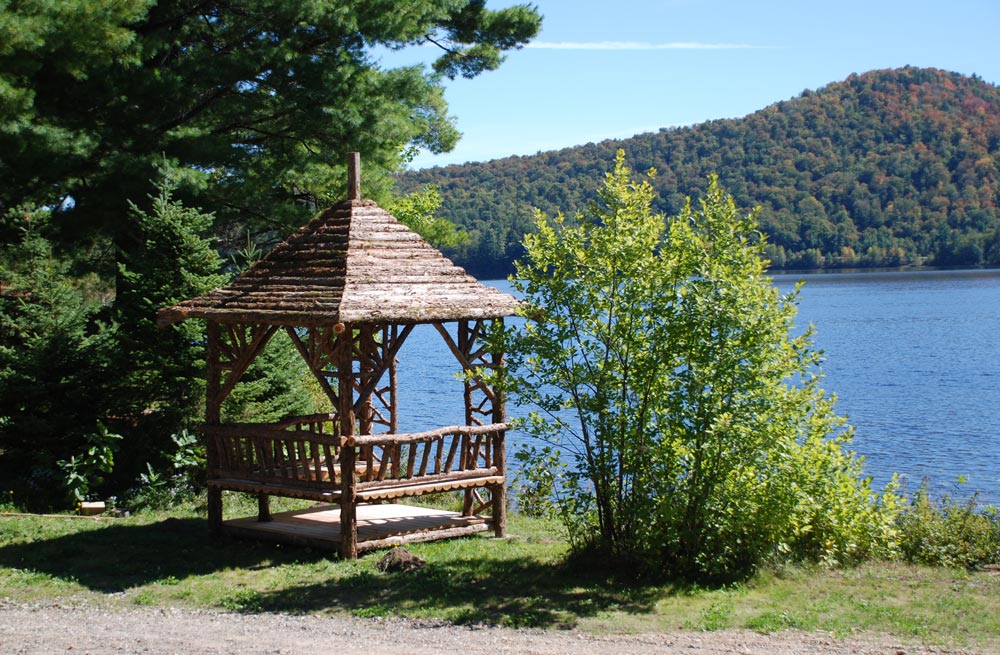 Natural wood summerhosue by a lake built with trees and branches titled the Tupper Lake Summerhouse