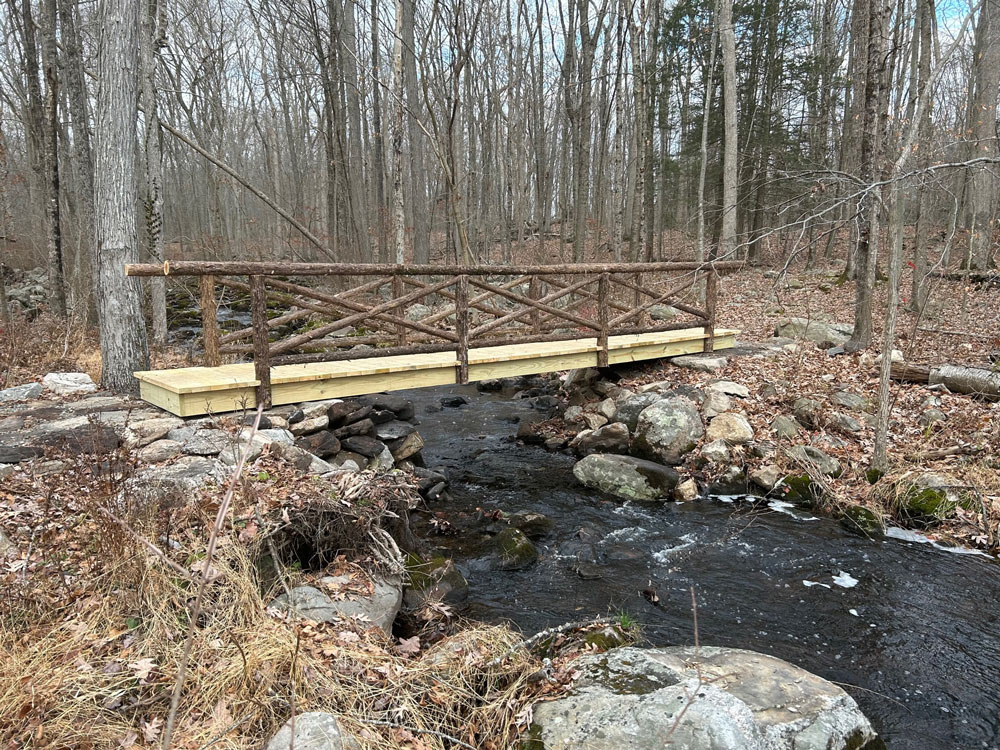 Rustic bridge built using bark-on trees and branches constructed for the Bartlett Arboretum