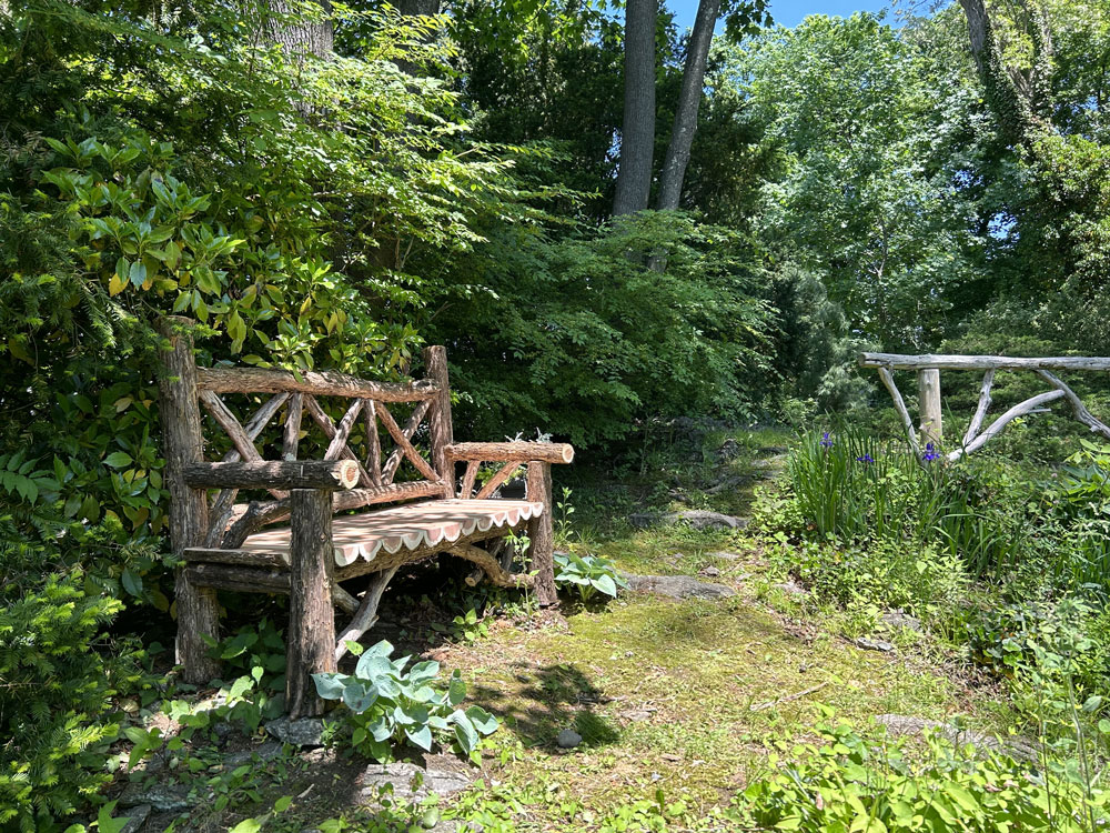 Outdoor park bench built in the rustic style using logs and branches titled the Milan Bench