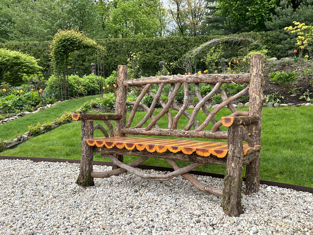 Outdoor park bench built in the rustic style using logs and branches titled the Putnam Bench