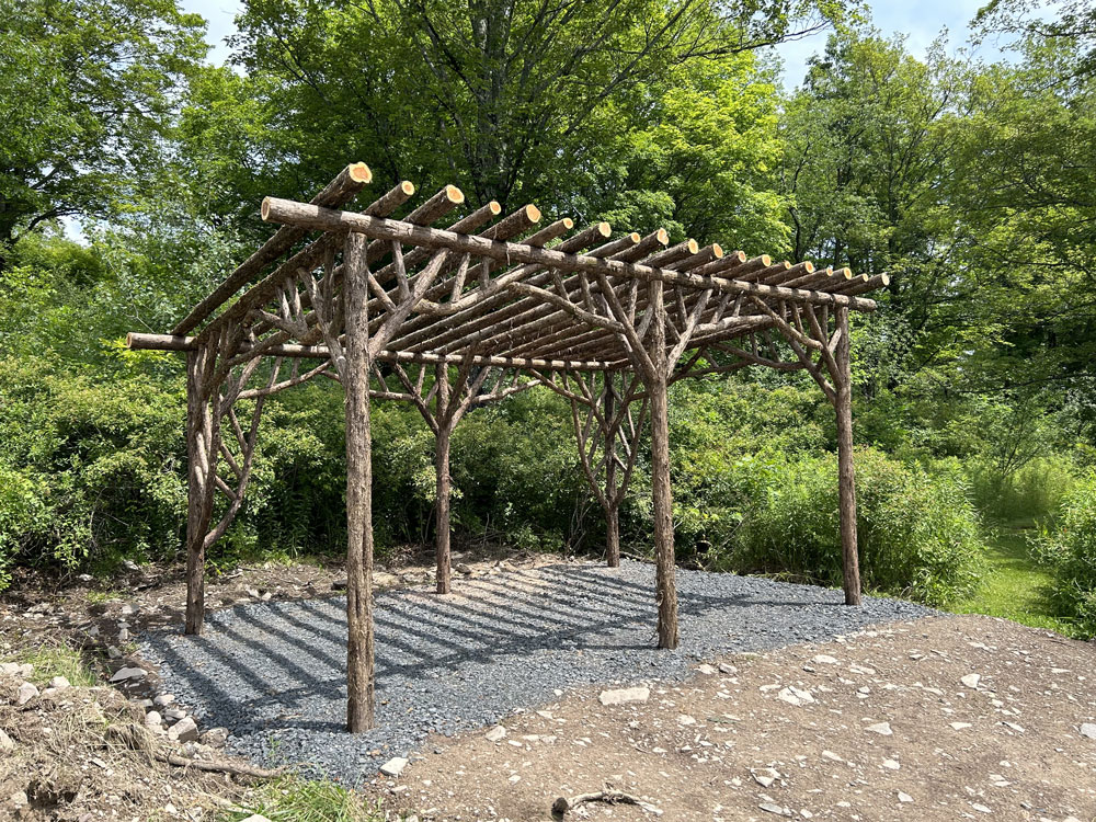 Rustic garden pergola built using bark-on trees and branches titled the Preston Hollow Pergola