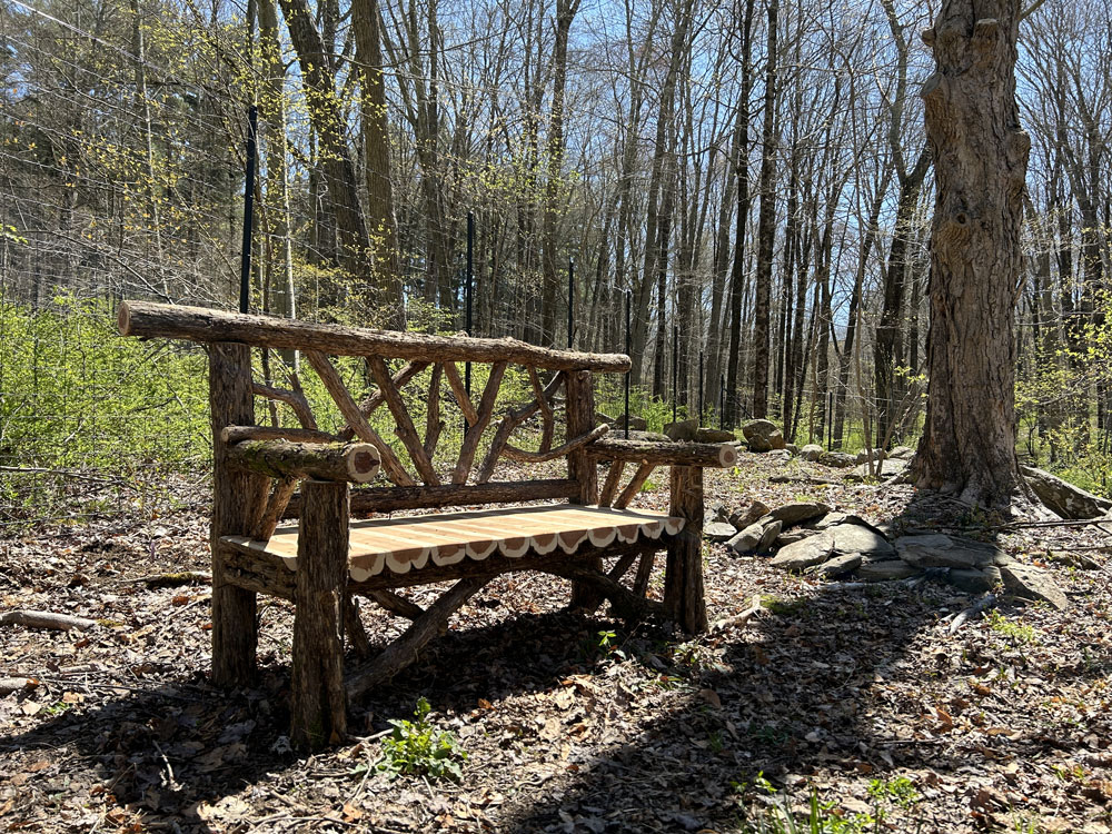 Outdoor park bench built in the rustic style using logs and branches titled the Bedford Bench 