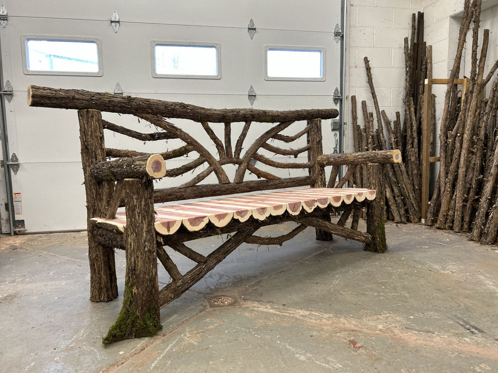 Outdoor rustic garden bench built using bark-on trees and branches titled the Catskill Bench 