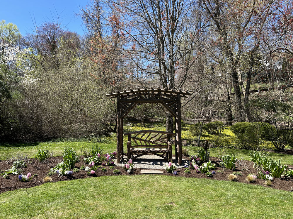 Outdoor arbor and bench built in the rustic style using logs and branches titled the Greenwich Arbor and Bench 