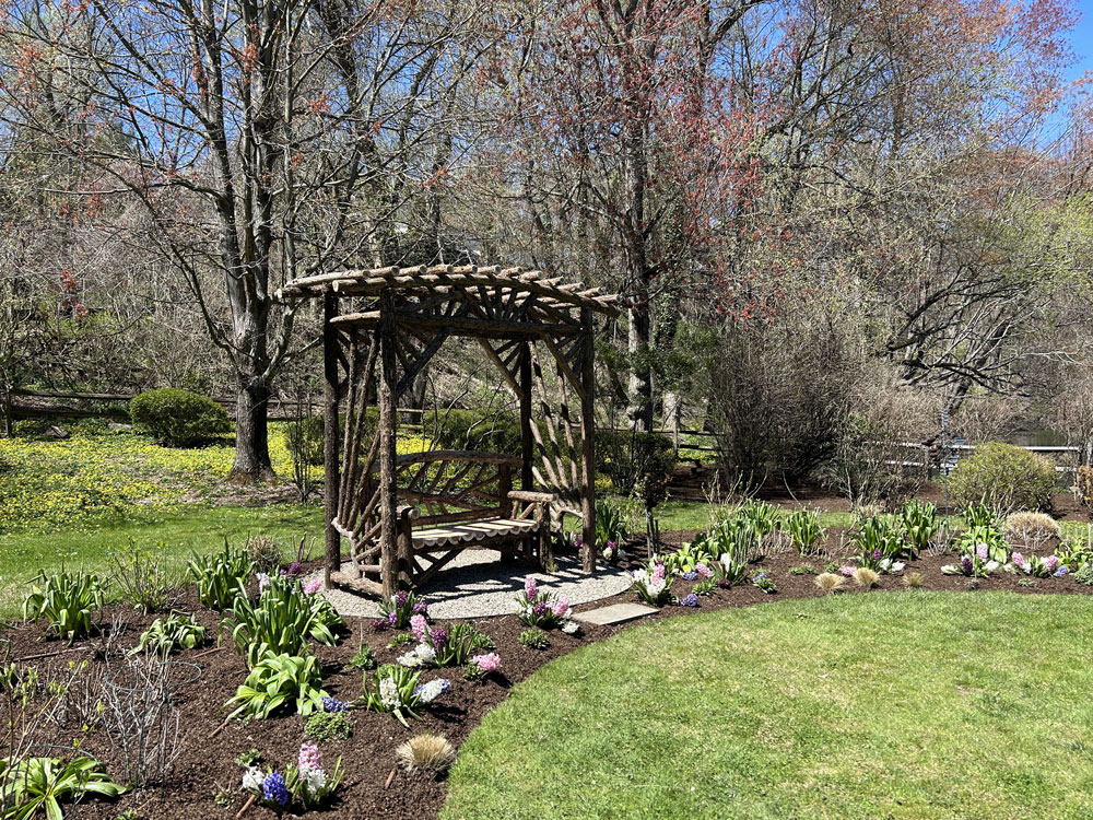 Outdoor arbor and bench built in the rustic style using logs and branches titled the Greenwich Arbor and Bench 