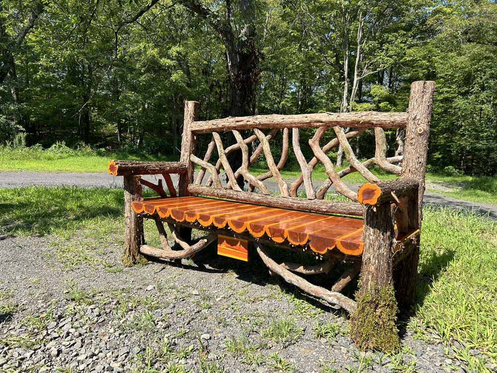 Outdoor park bench built in the rustic style using logs and branches titled the Mohonk Putnam Bench