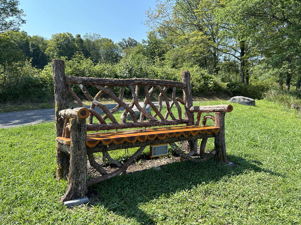 Outdoor park bench built in the rustic style using logs and branches titled the Mohonk Putnam Bench