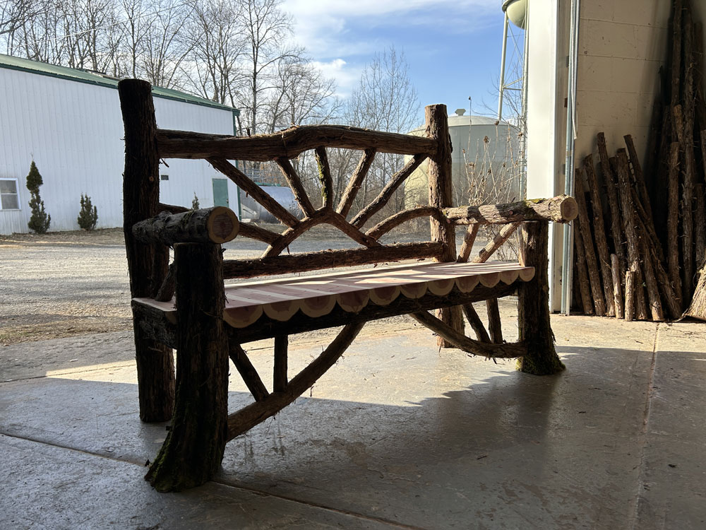 Outdoor rustic garden bench built using bark-on trees and branches titled the Millbrook Sunburst Bench