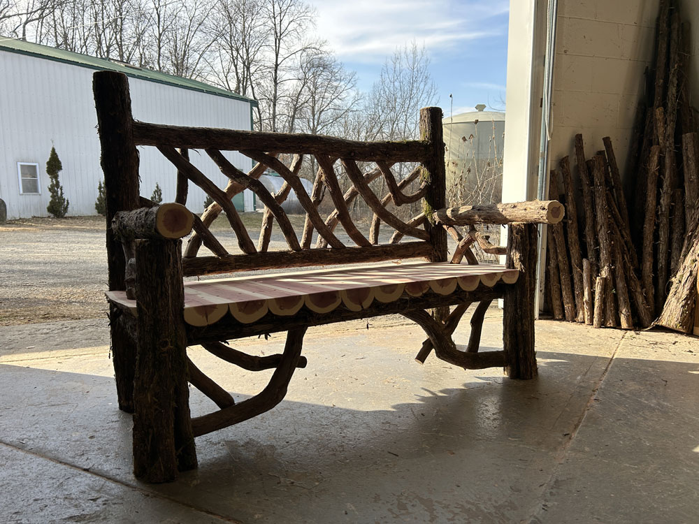 Outdoor rustic garden bench built using bark-on trees and branches titled the Putnam Bench