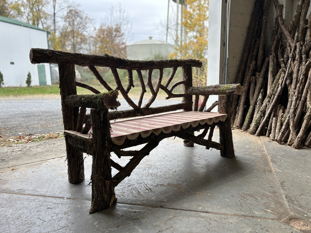 Exterior twig bench built from cedar logs titled the Falling Waters Bench