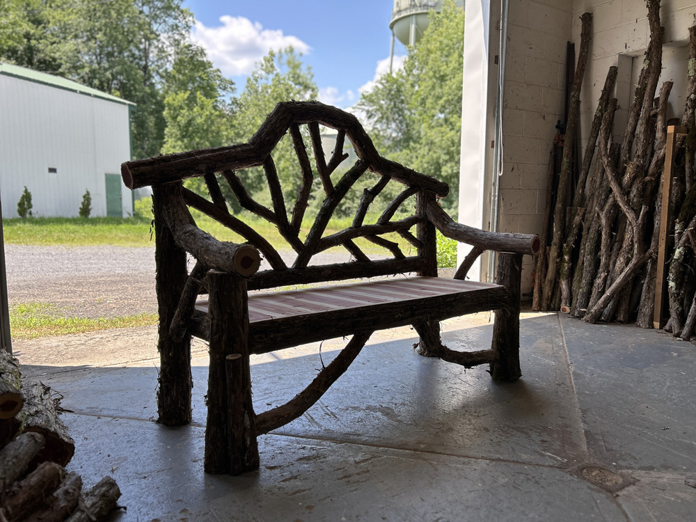 Outdoor rustic garden bench built using bark-on trees and branches titled the Garrison Bench