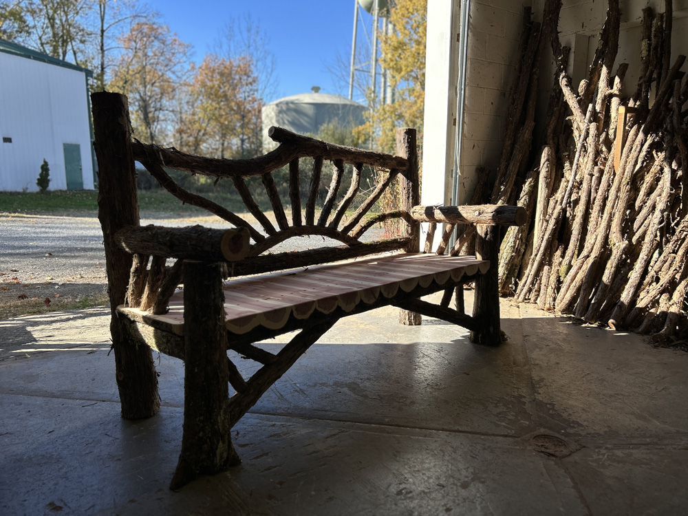 Outdoor park bench built in the rustic style using logs and branches titled the Millbrook Sunburst Bench