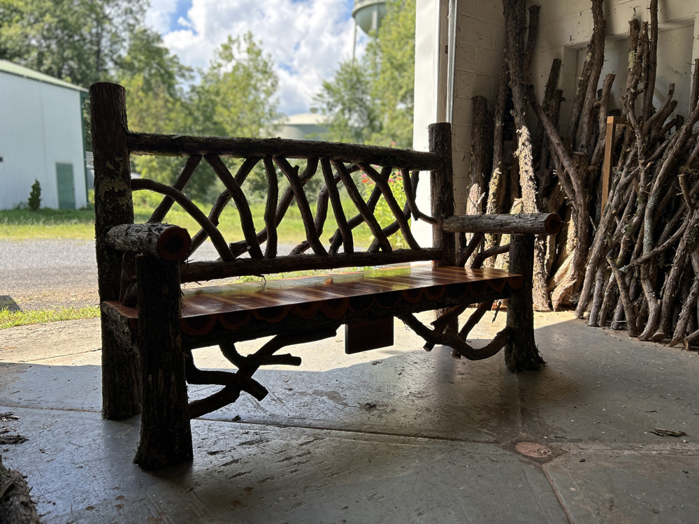 Outdoor park bench built in the rustic style using logs and branches titled the Mohonk Bench
