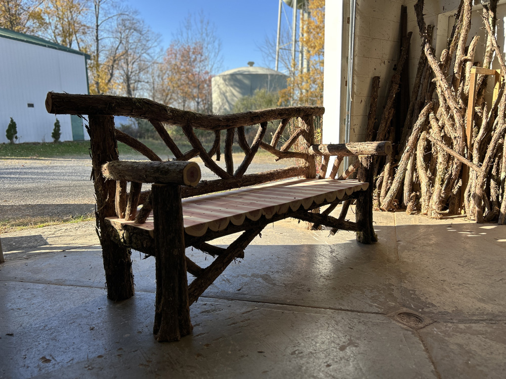 Outdoor rustic garden bench built using bark-on trees and branches titled the Falling Waters Bench