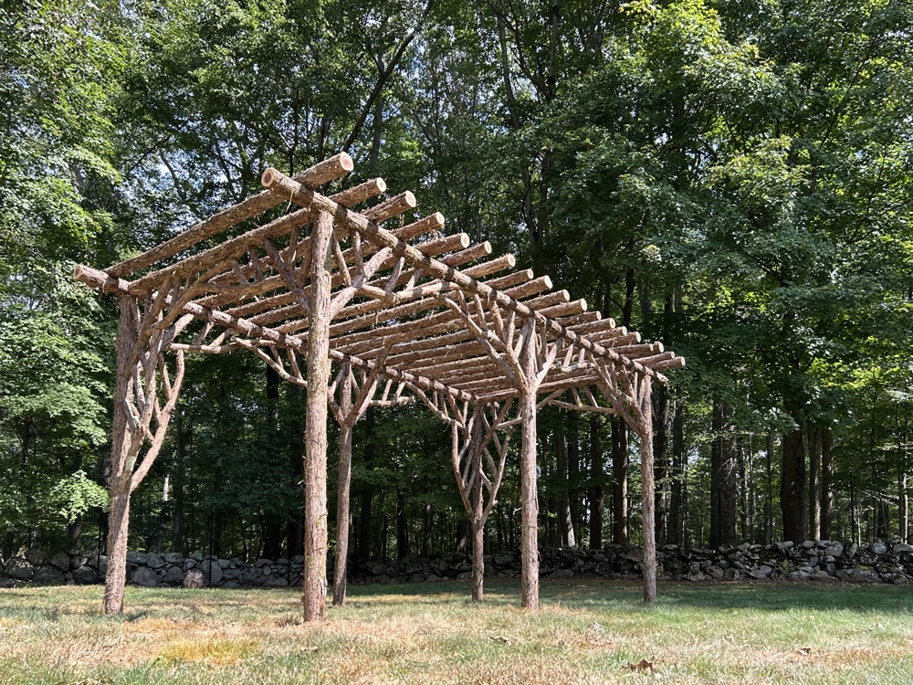 Rustic natural pergola made from bark-on cedar logs, twigs, and branches titled the Stamford Pergola