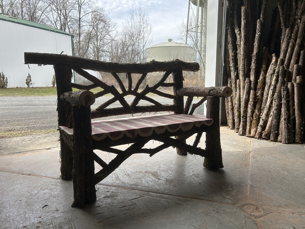 Outdoor park bench built in the rustic style using logs and branches titled the Catskill Bench