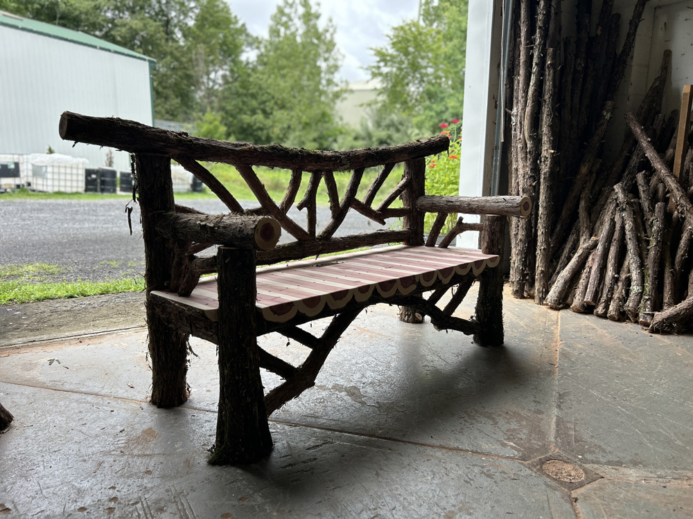 Exterior twig bench built from cedar logs titled the Falling Waters Bench