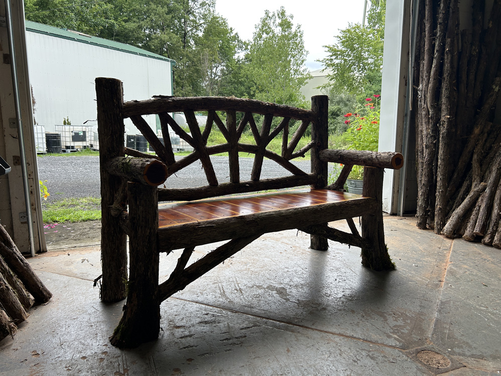Natural wood bench built with trees and branches titled the Maverick Bench