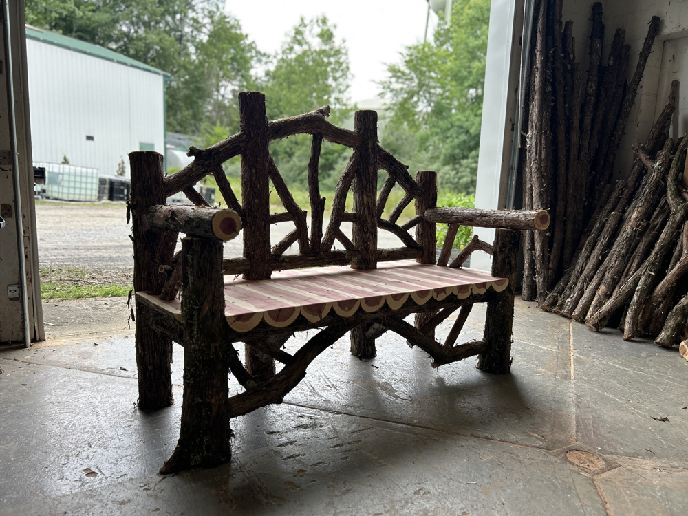 Outdoor rustic garden bench built using bark-on trees and branches titled the Poet's Bench