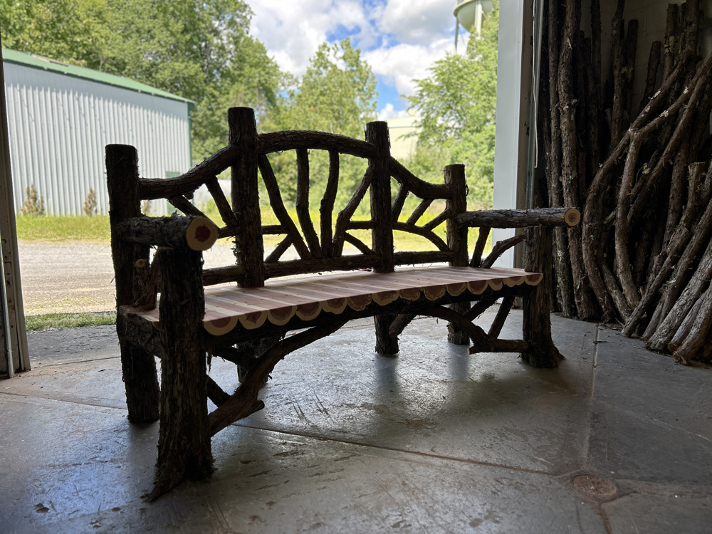 Outdoor rustic garden bench built using bark-on trees and branches titled the Poet's Bench