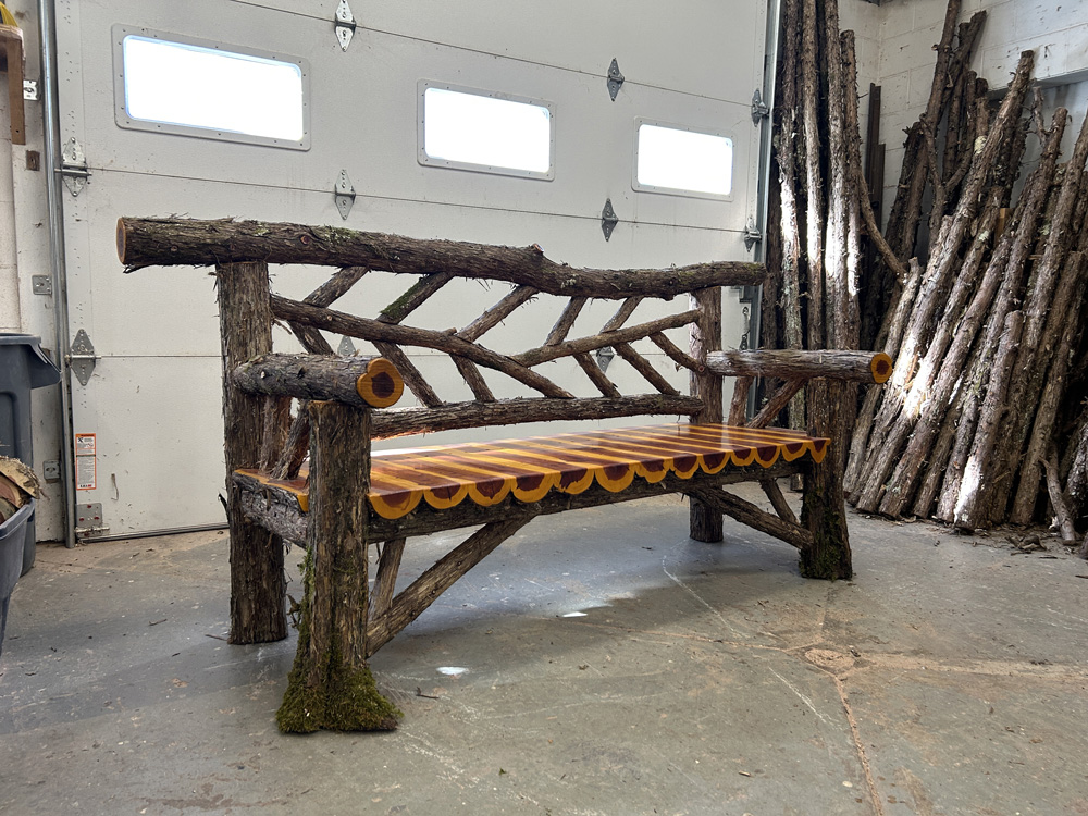 Outdoor rustic garden bench built using bark-on trees and branches titled the Falling Waters Bench
