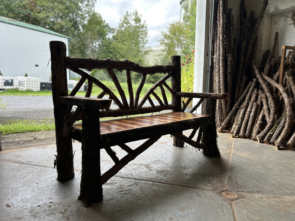 Outdoor rustic garden bench built using bark-on trees and branches titled the Taconic Bench