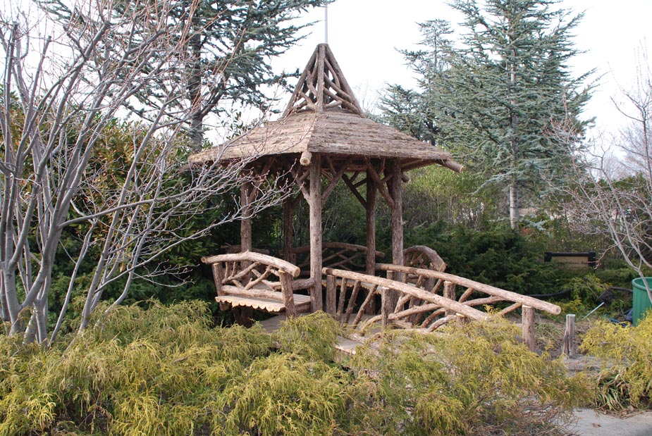 Rustic gazebo and bridge built using bark-on trees and branches installed at Hofstra University Arena Garden