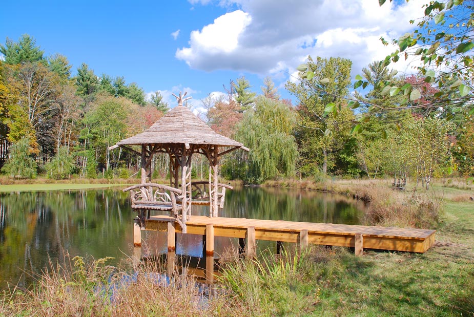 Rustic gazebo and dock built using bark-on trees and branches titled the Williams Gazebo & Dock
