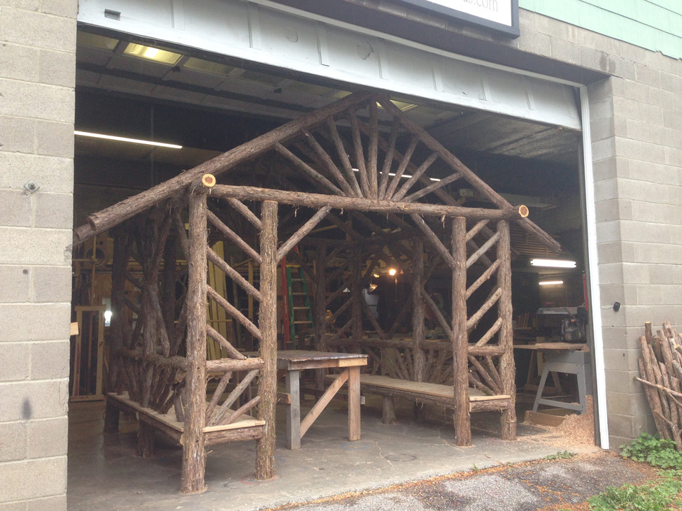 Outdoor sitting shelter built in the rustic style using logs and branches titled the Skyview Entrance Arbor