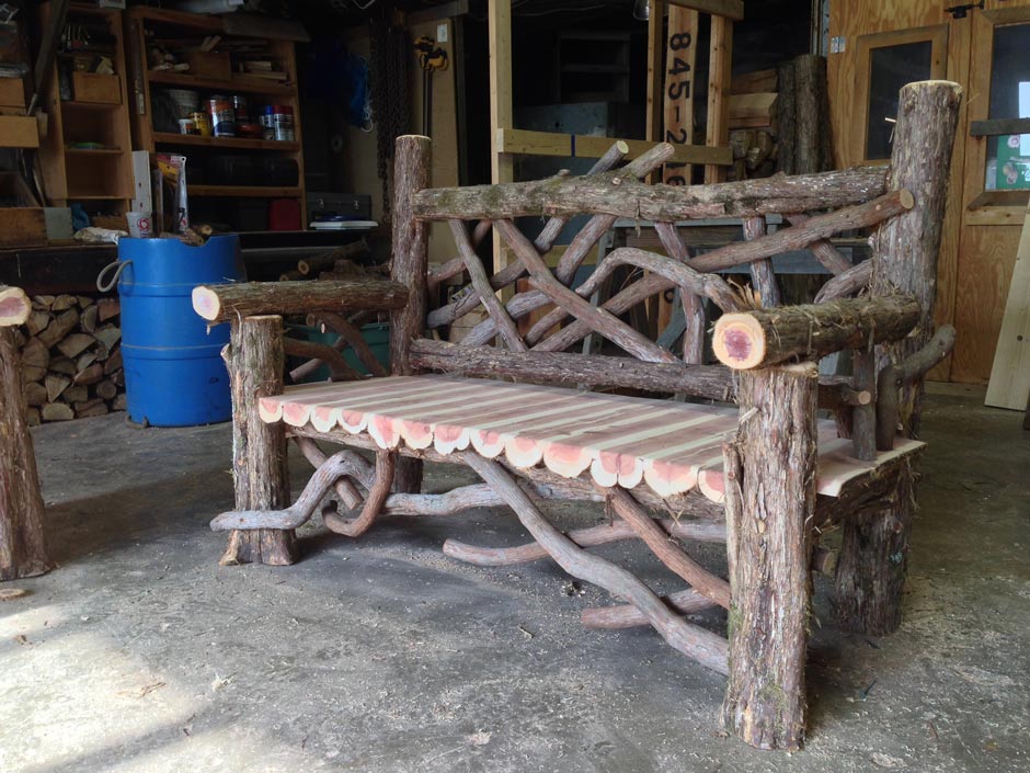 Outdoor park bench built in the rustic style using logs and branches titled the Midler Putnam Bench