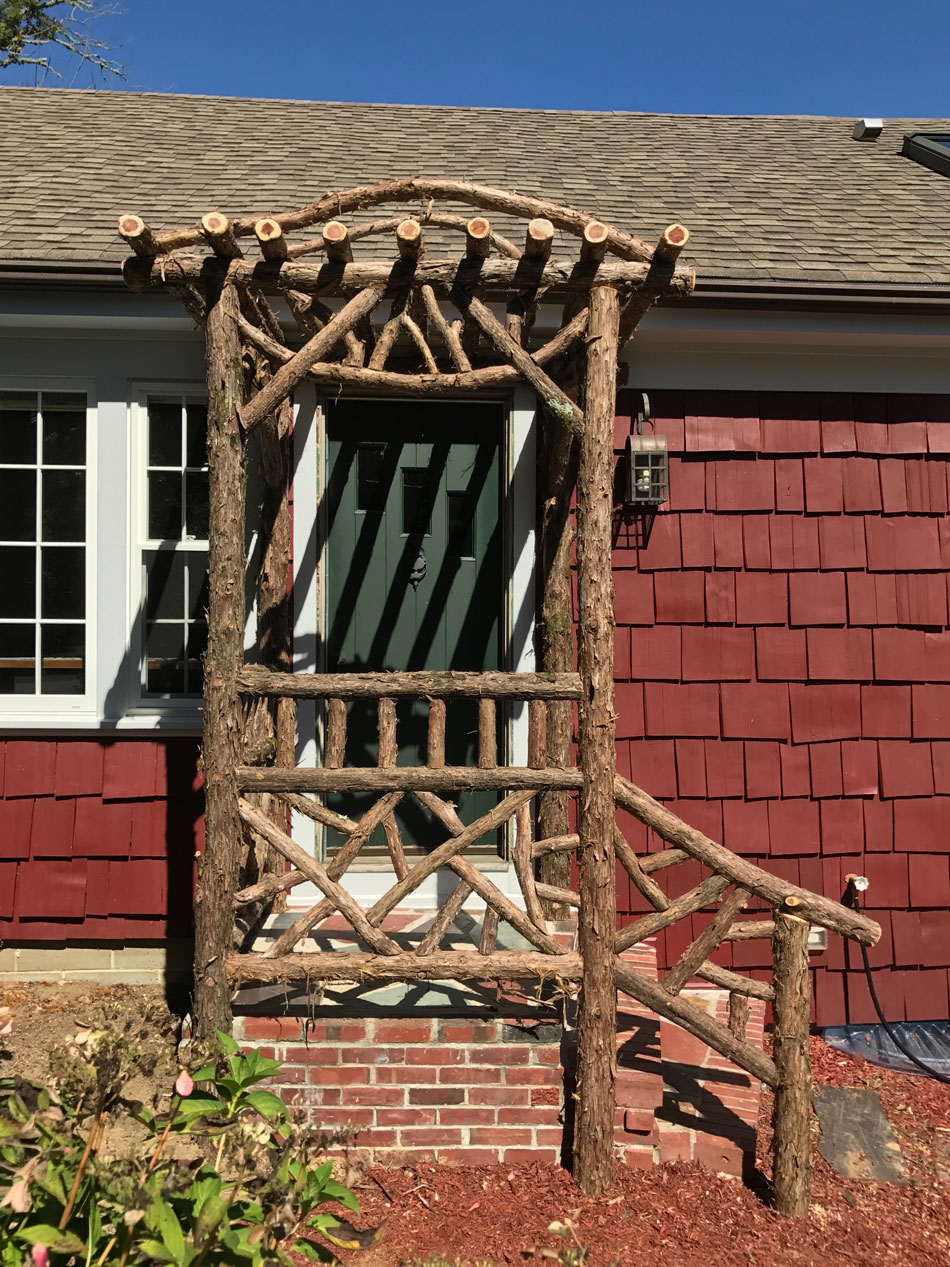 Rustic natural arbor made from bark-on cedar logs, twigs, and branches titled the Melikan Entrance Arbor