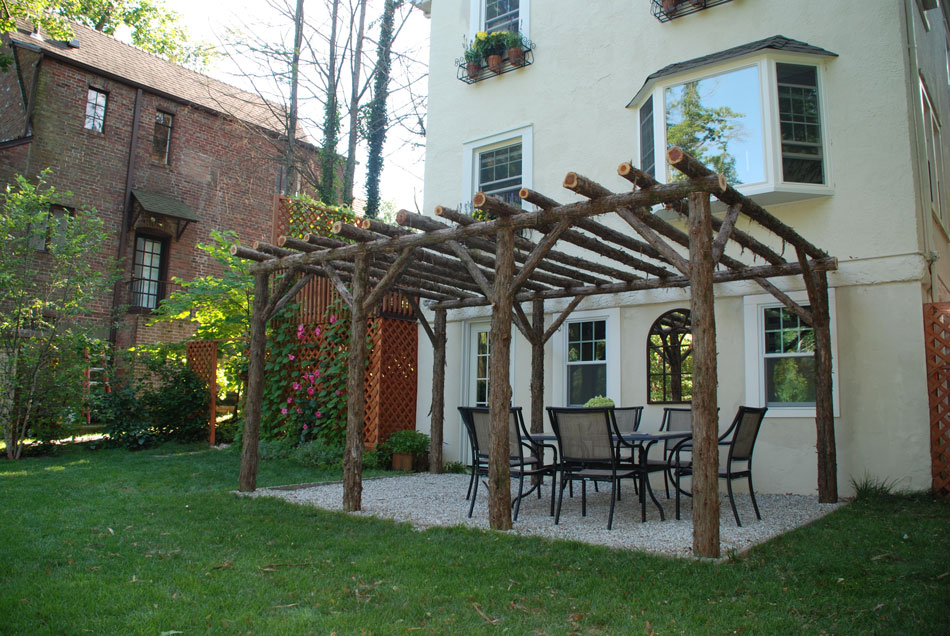Rustic natural pergola made from bark-on cedar logs, twigs, and branches titled the Larchmont Pergola