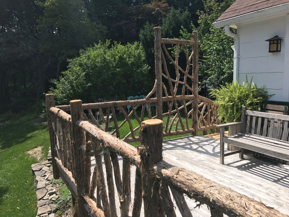 Rustic deck railings custom built using cedar trees and branches titled the Burroughs Deck Railings