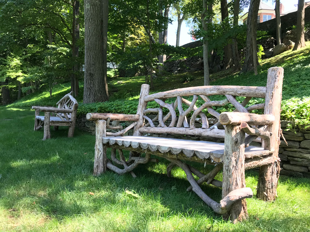 Outdoor rustic garden bench built using bark-on trees and branches.