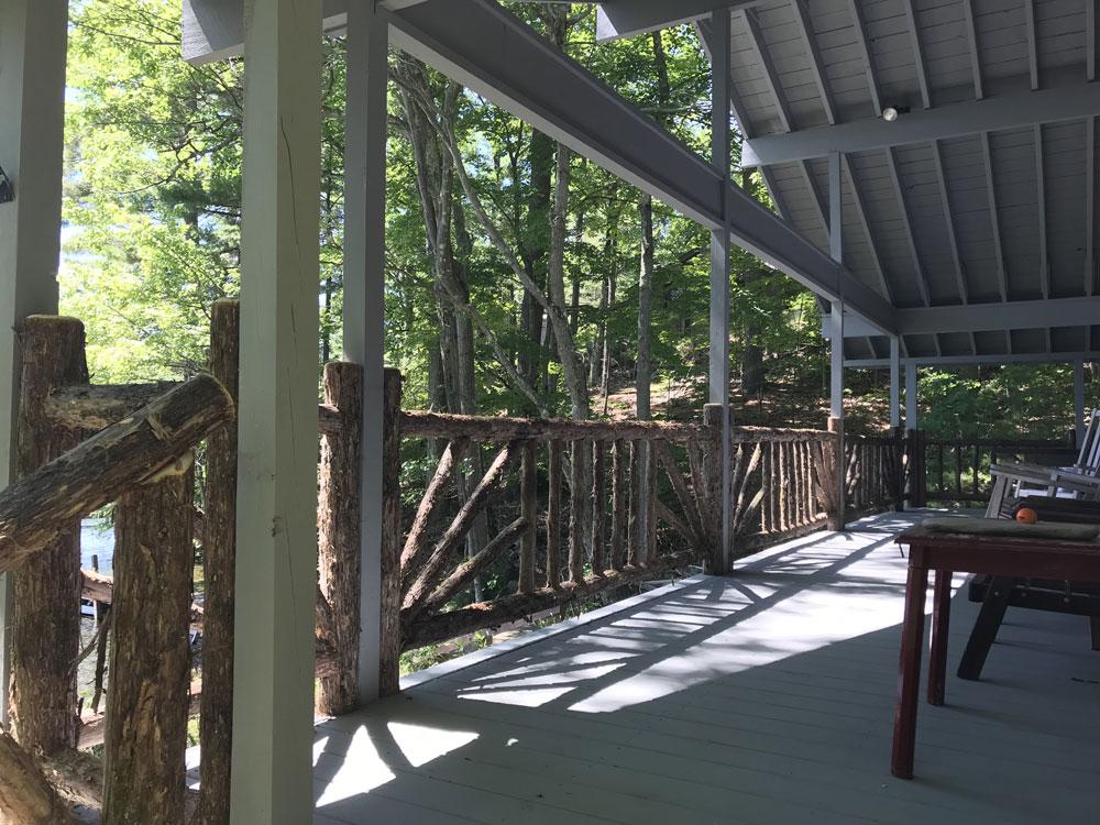 Railings built in the rustic style using logs and branches titled the Porch Railings at Hullets Landing