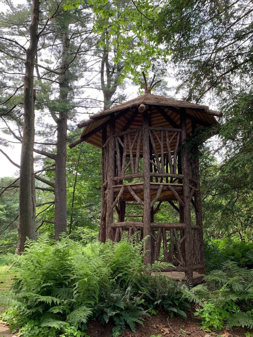 Outdoor rustic tree tower built using bark-on trees and branches titled the Bedford Tower
