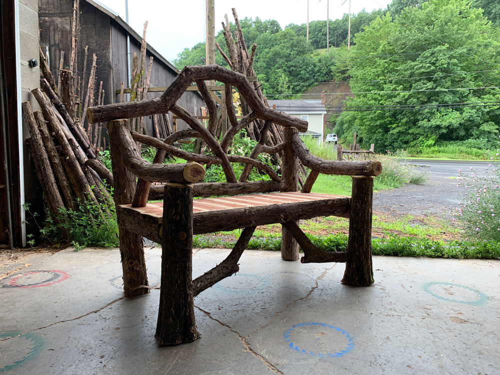 Outdoor park bench built in the rustic style using logs and branches titled the Garrison Bench