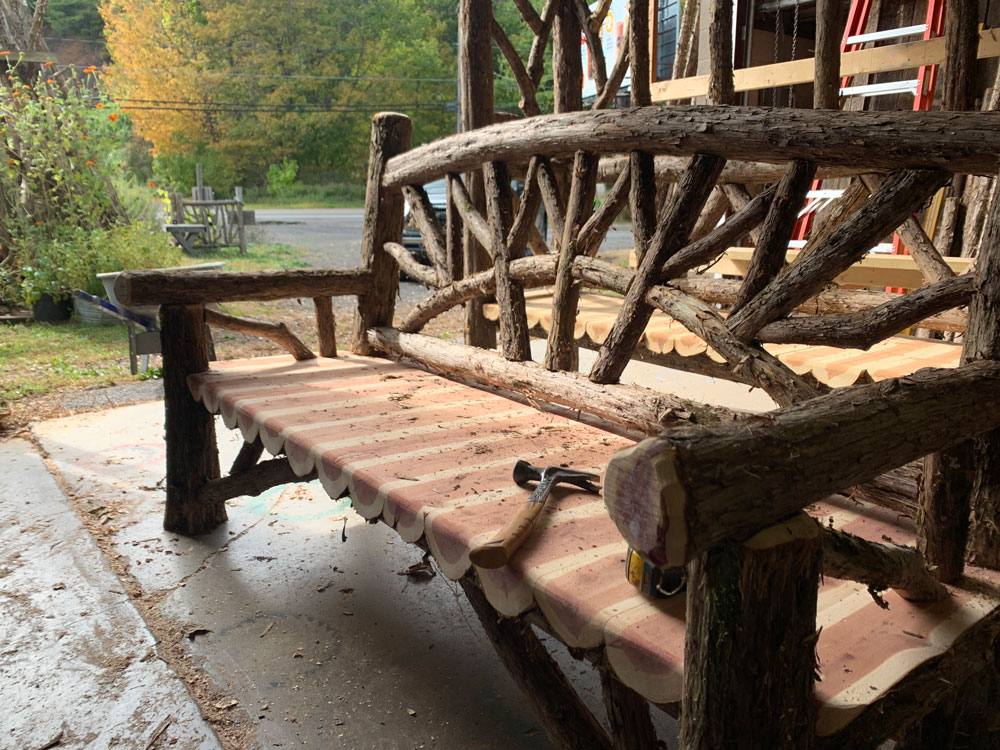 Exterior twig bench built from cedar logs titled the Maverick Bench