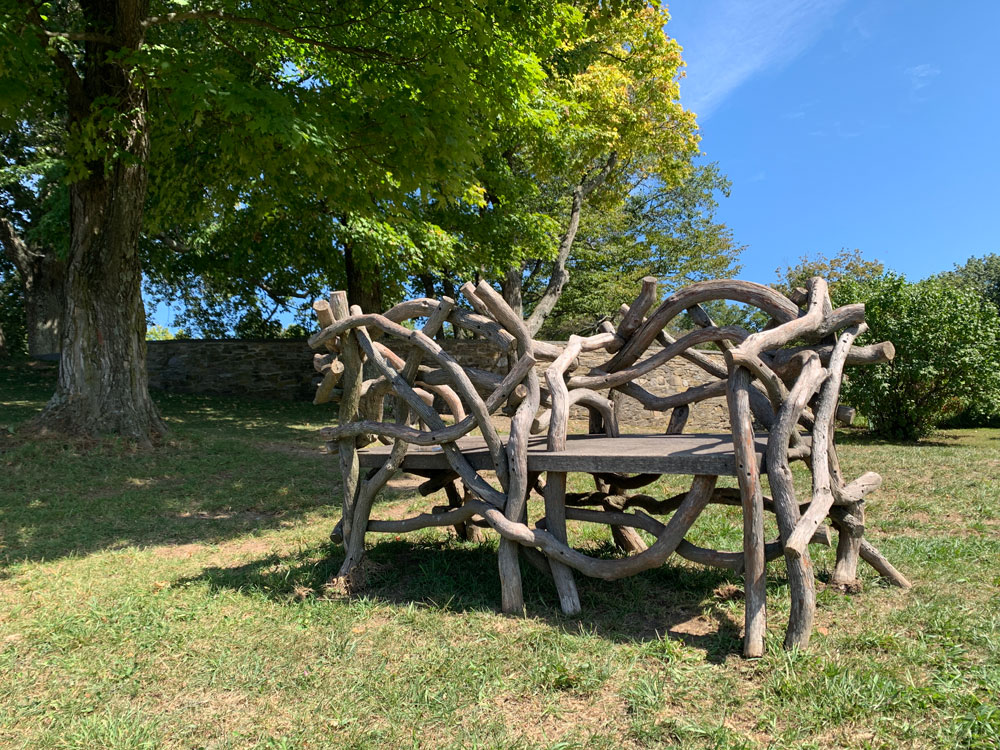 Outdoor rustic park bench built using mountain laurel trees and branches titled the Olana Couples Bench
