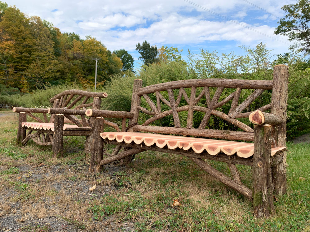 Outdoor rustic garden bench built using bark-on trees and branches titled the Poet's Benches