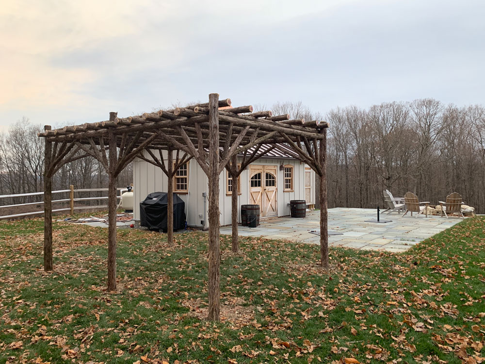 Rustic garden pergola built using bark-on trees and branches titled the Pine Plains Pergola