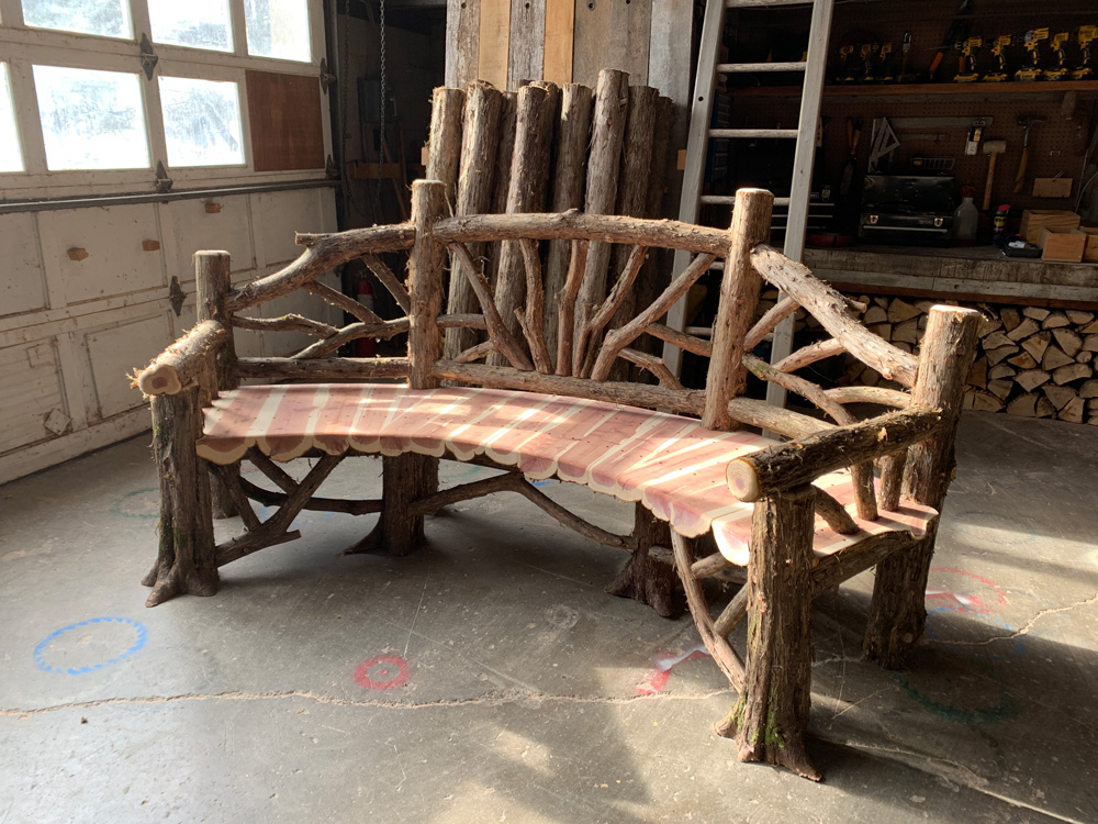 Outdoor rustic garden bench built using bark-on trees and branches titled the Poet's Bench